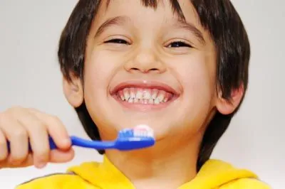 young child smiling while holding his toothbrush